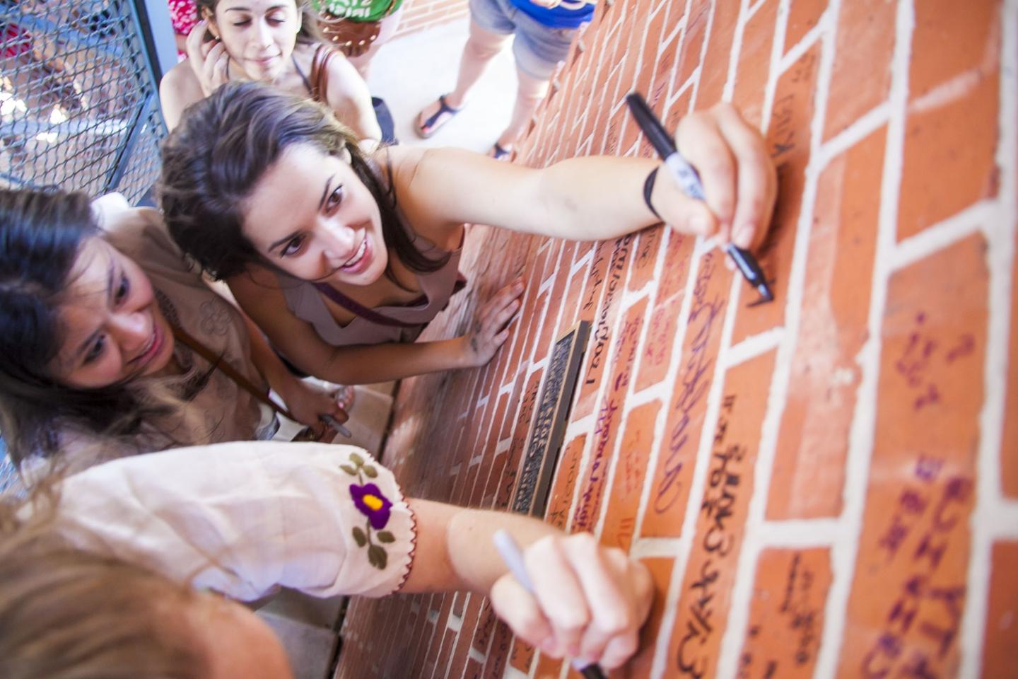 三名女学生在默奇森塔的砖上签名