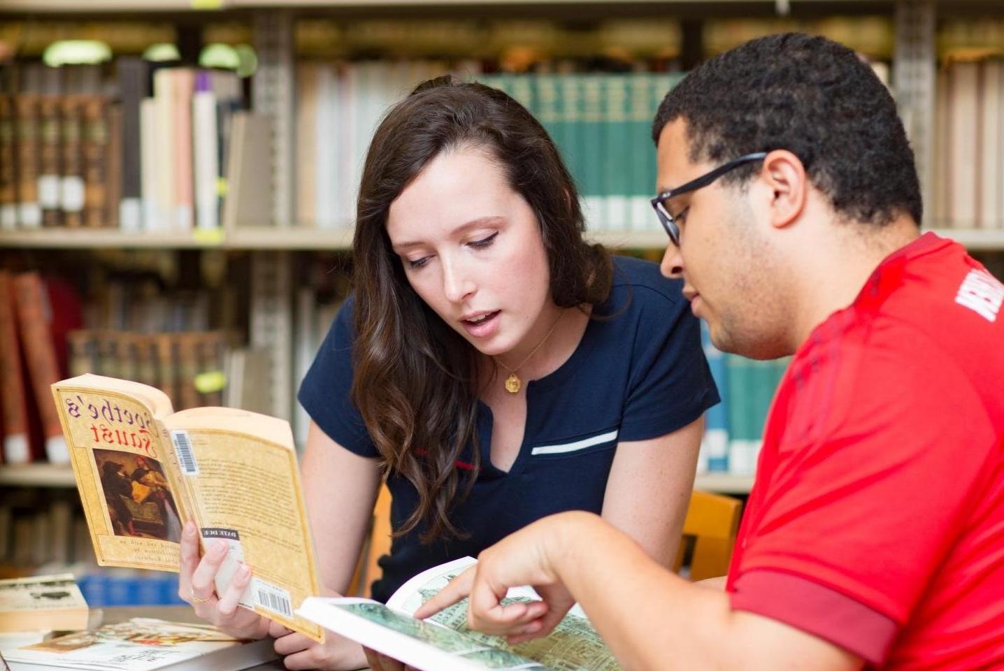 Two students look at map inside of a book